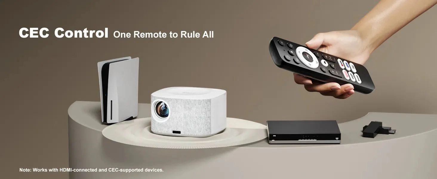 A hand holding the ONO5Pro-W remote beside the projector, a games console and a set-top box